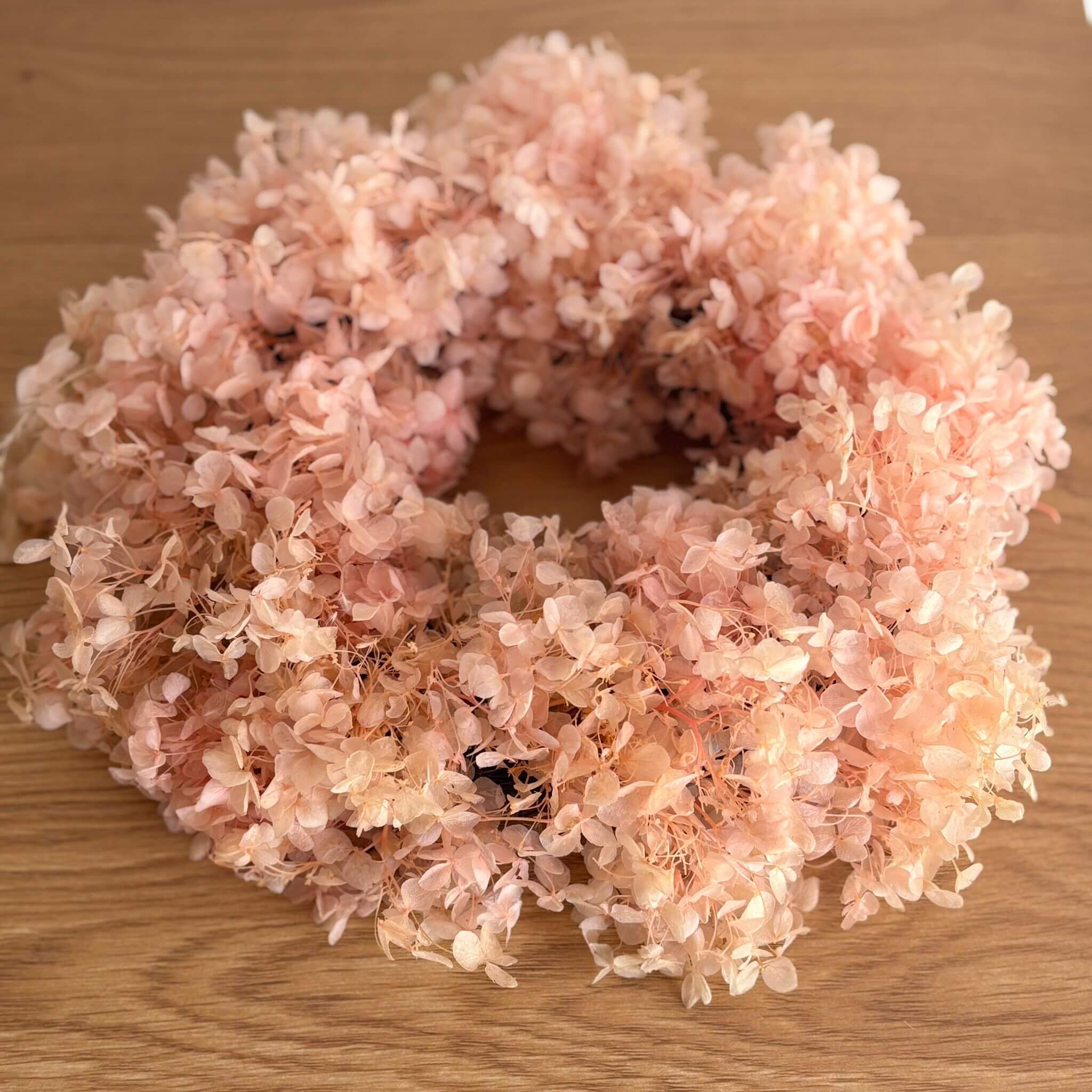 Puristischer Trockenblumenkranz aus rosa Rispenhortensien für stilvolle Raumdekoration.