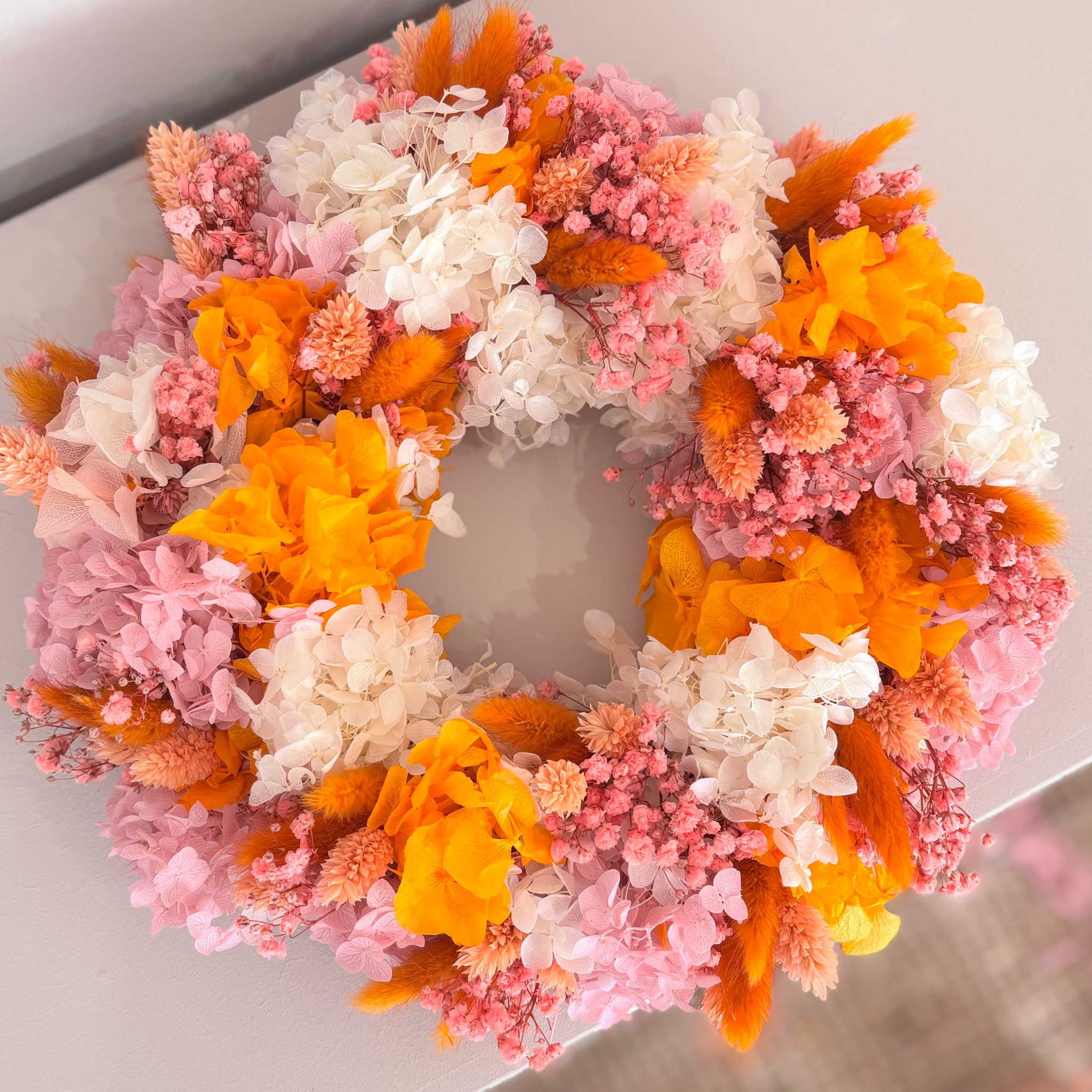 Elegant holiday wreath with four pink candles, adorned with greenery and festive decorations. Perfect for seasonal decor.