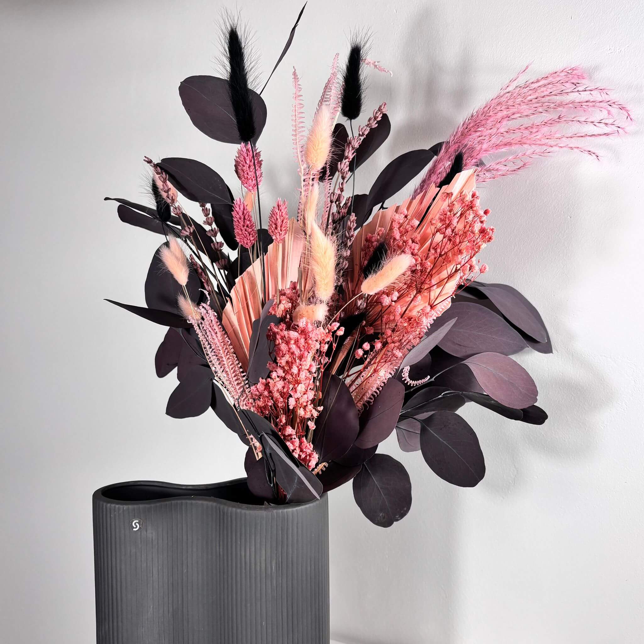 Trockenblumenstrauß "Dark Touch of Pink" mit rosa und roten Tönen in modernem schwarzen Vase.