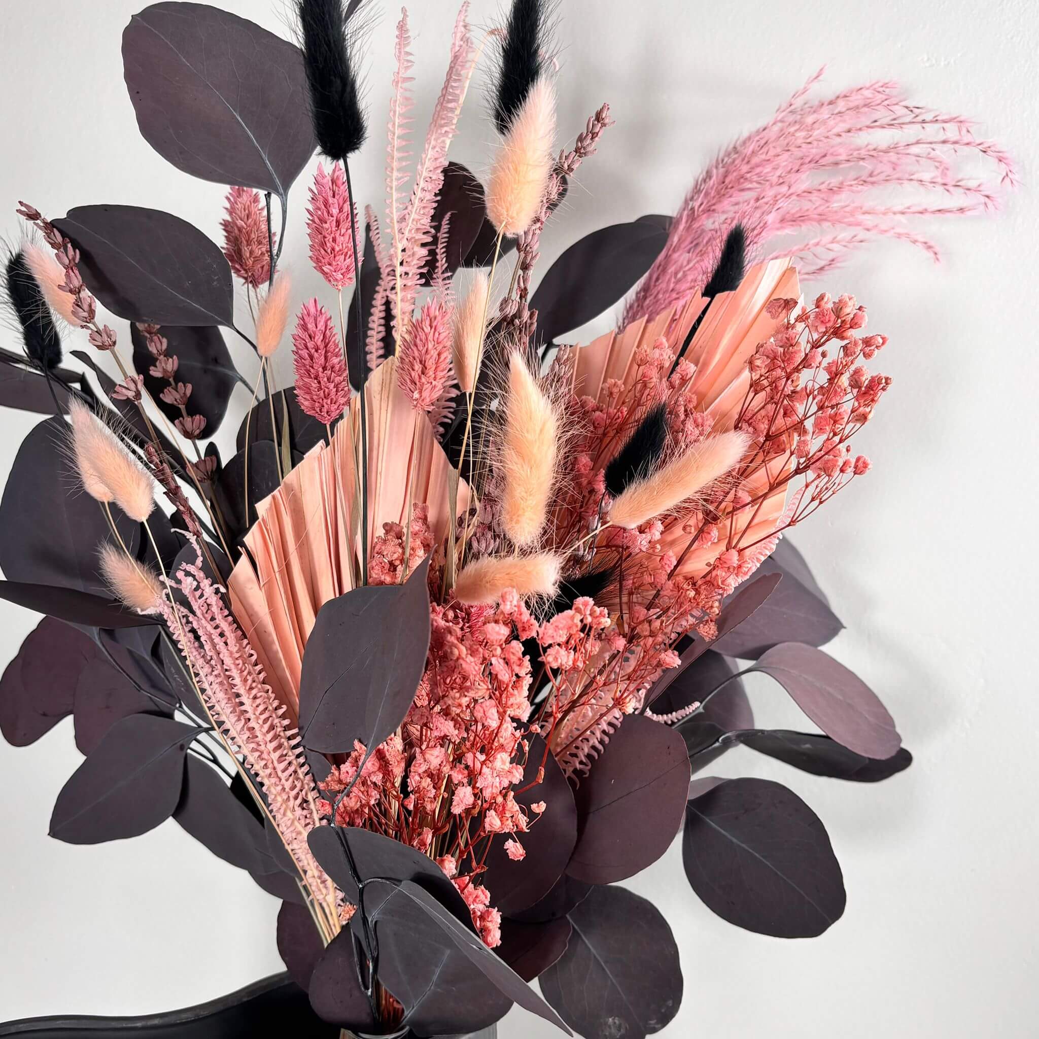 Trockenblumenstrauß 'Dark Touch of Pink' mit rosa und roten Tönen, Lagurus und exotischem Palmblatt.