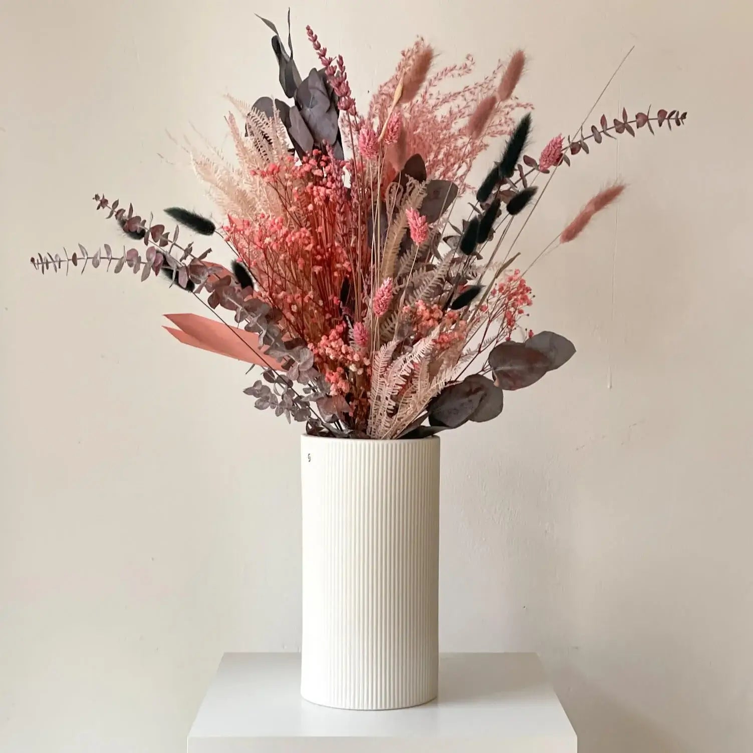 Elegant floral arrangement in soft pink tones displayed in a white ribbed vase, perfect for adding charm to any space.